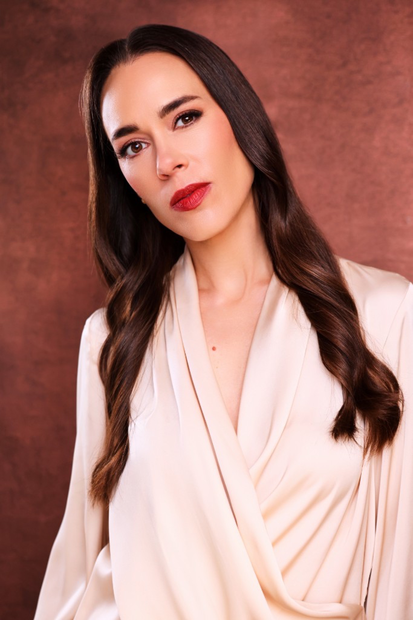 Shannon Lepard in a cream satin wrap against a terracotta backdrop